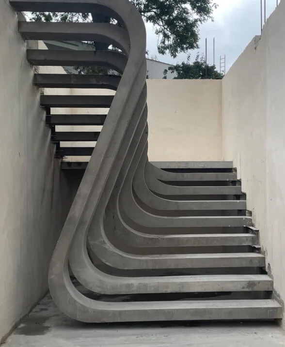 Moderne, geschwungene Betontreppe mit freitragenden Stufen in einem minimalistischen Innenraum nach der Betonierung Moderne, geschwungene Betontreppe mit freitragenden Stufen in einem minimalistischen Innenraum nach der Betonierung