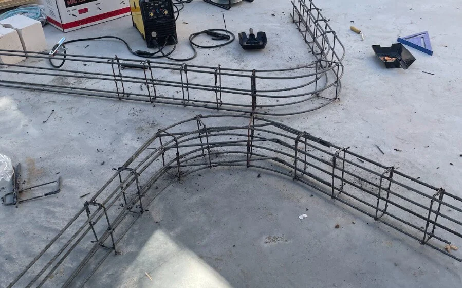 Gebogene Bewehrung aus Stahl für eine geschwungene Betontreppe auf einer Baustelle, vorbereitet zur Betonierung Gebogene Bewehrung aus Stahl für eine geschwungene Betontreppe auf einer Baustelle, vorbereitet zur Betonierung