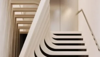 Moderne, skulpturale Betontreppe mit organischer Form in einem minimalistischen Innenraum
