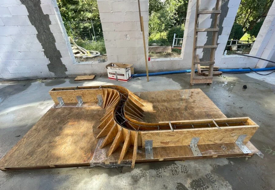 Holzschalung für eine geschwungene Betontreppe im Rohbau, vorbereitet für die Betonierung im Innenbereich Holzschalung für eine geschwungene Betontreppe im Rohbau, vorbereitet für die Betonierung im Innenbereich